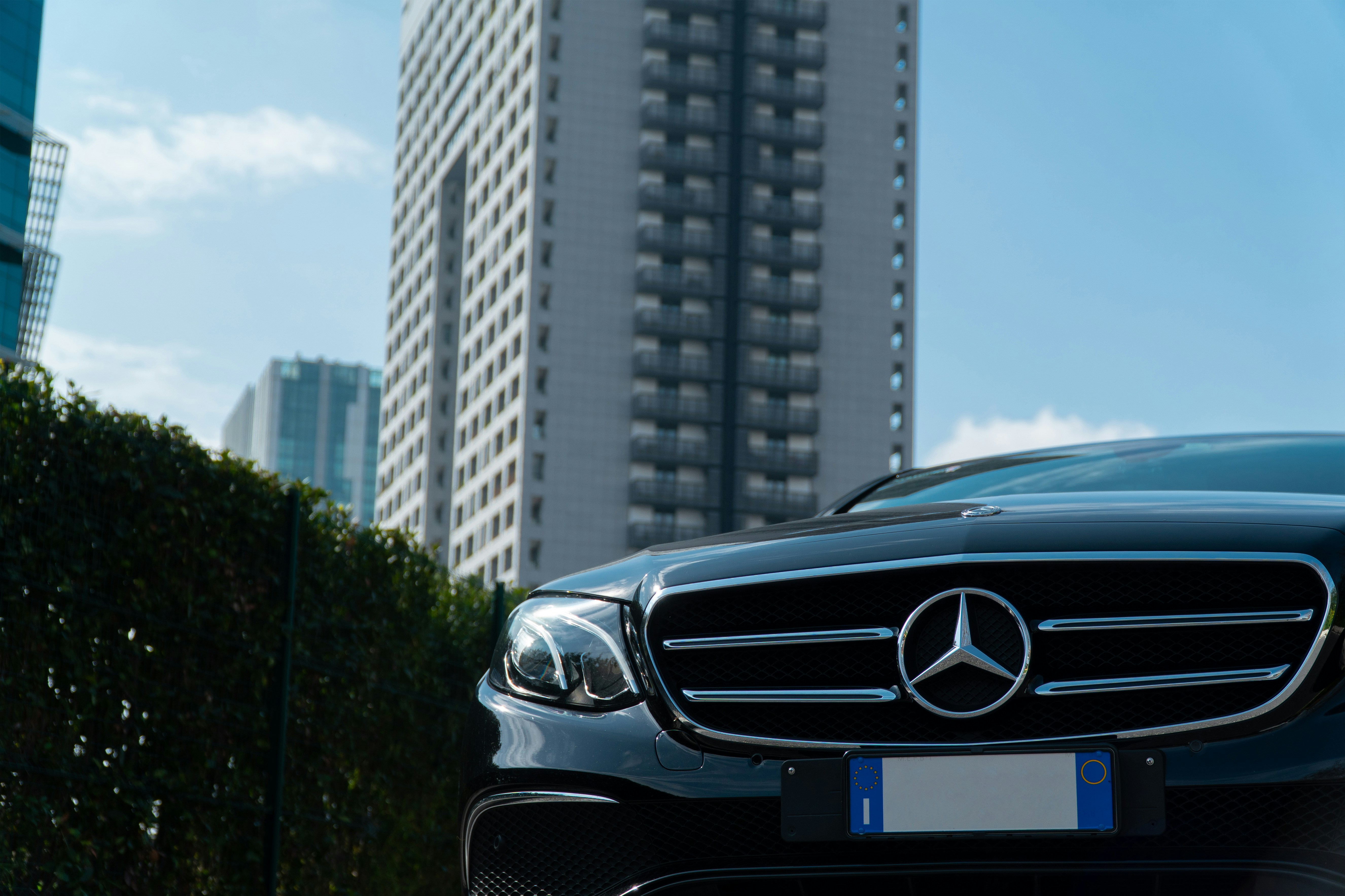 Black executive sedan parked beside city offices